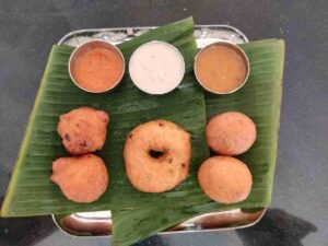 Medu vada and bonda served on banana leaf with coconut chutney and sambar at Lingaiah Tiffin Centre Mallepally