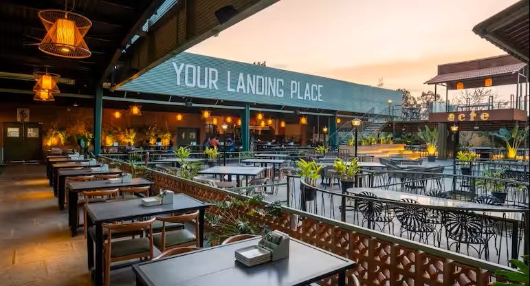 Acre Bengaluru outdoor seating area in Yelahanka with open-air dining tables and warm ambient lighting.