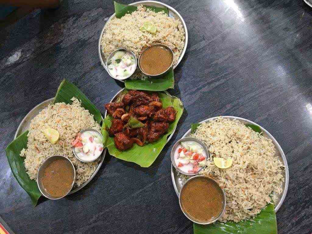 Hotel Hanumanthu Mysuru mutton pulao meal with gravy, raita and chicken fry served on banana leaf