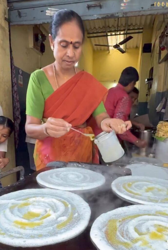 Cook preparing crispy dosa with ghee on hot tawa at Mahesh Hotel Doddaballapur.