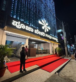 Pooja Bakery new branch in HBR Layout Bengaluru with bright decorative lights, grand entrance, red carpet walkway, and illuminated signage at night.