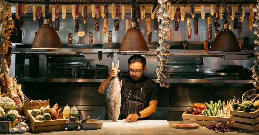 Chef preparing fresh seafood in an open kitchen at Acre Bengaluru restaurant in Yelahanka.