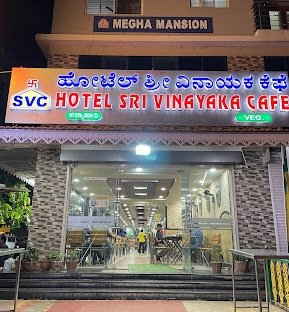 Front entrance of Sri Vinayaka Cafe Kadur with illuminated signboard during evening hours.