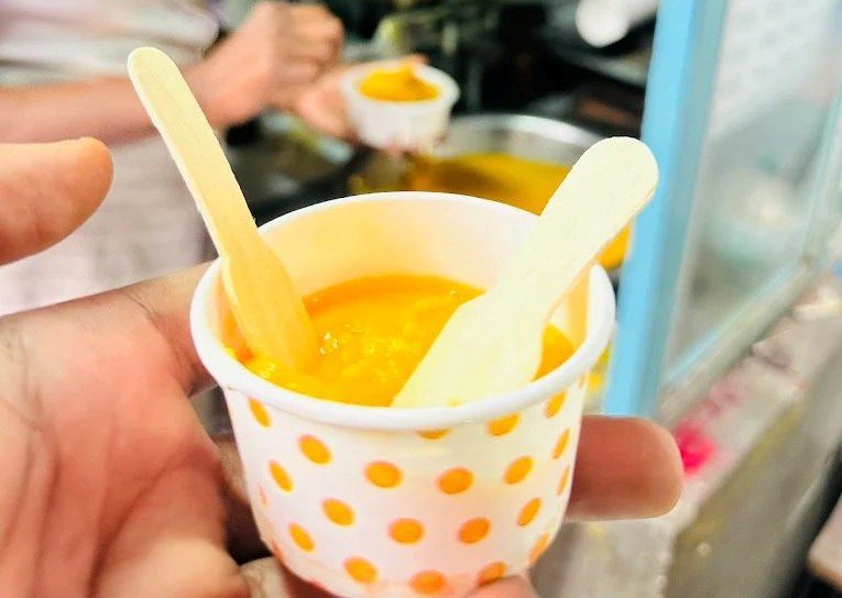 Cup of hot Kollegala Badam Halwa served fresh with pure ghee at the traditional sweet house.