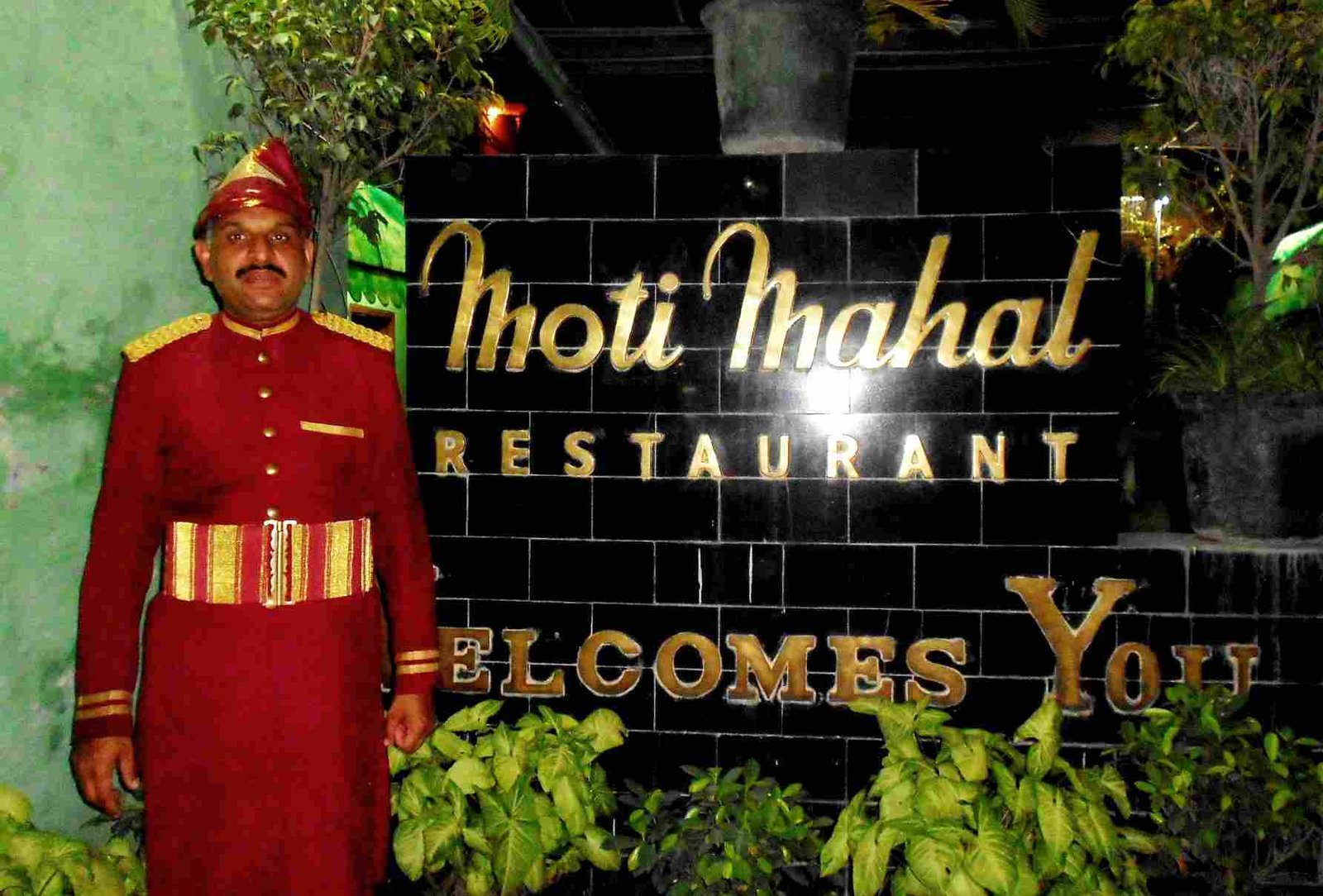Moti Mahal Restaurant entrance in Delhi with traditional doorman in red uniform standing beside signboard