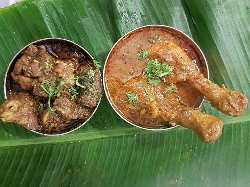 Chicken leg masala and mutton curry served on banana leaf at Shivaji Military Hotel Bengaluru.