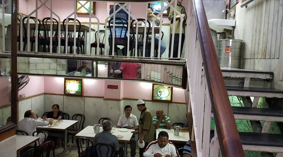 Interior dining area of Karim’s restaurant in Old Delhi with customers enjoying traditional Mughlai dishes.