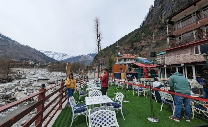 Riverside seating at Café 1947 in Manali with mountain views and outdoor tables