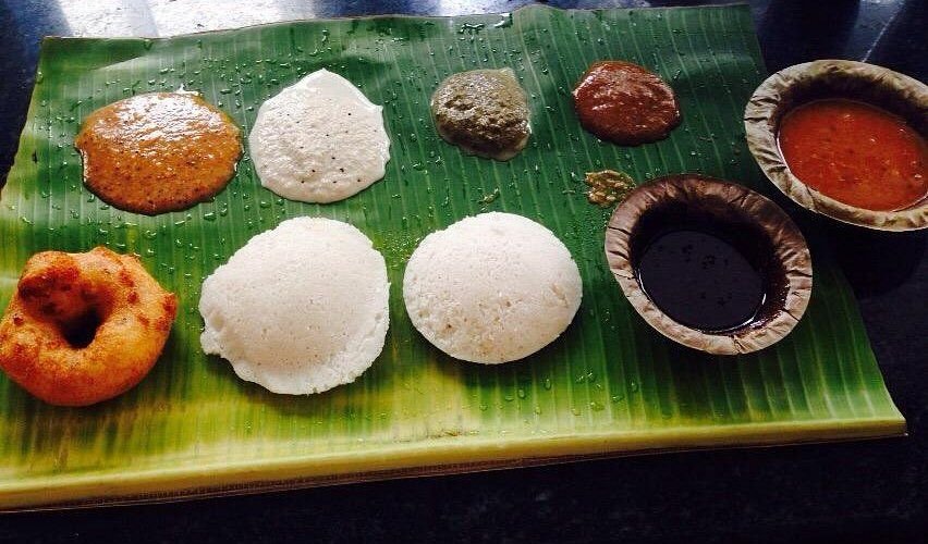 Soft idlis with medu vada, multiple chutneys, and sambar served on banana leaf at Murugan Idli Shop Chennai