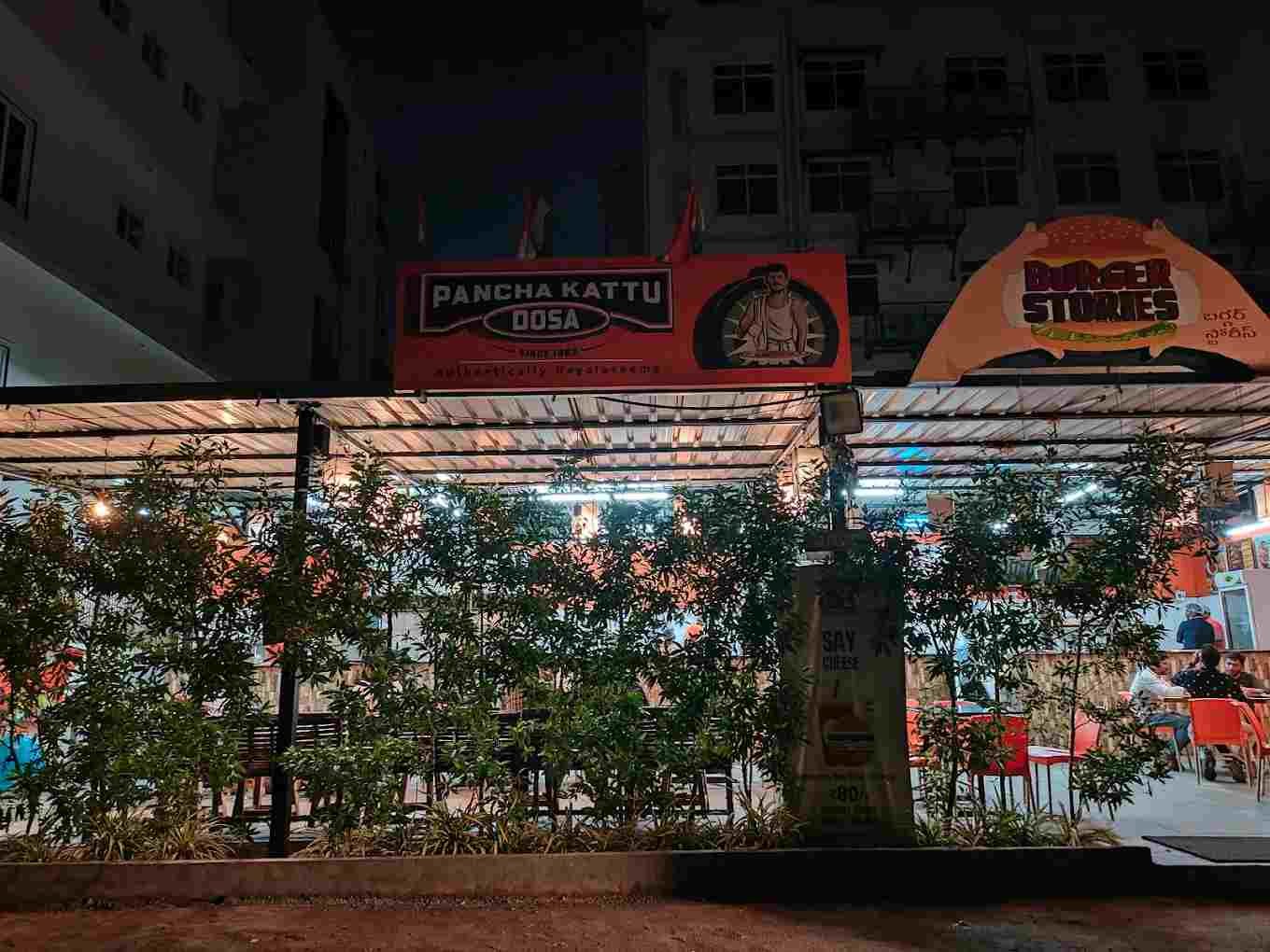 Pancha Kattu Dosa restaurant exterior night view with bright signage and outdoor seating area