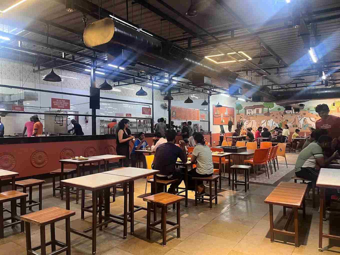 Pancha Kattu Dosa restaurant interior with seating area, open kitchen, and customers dining