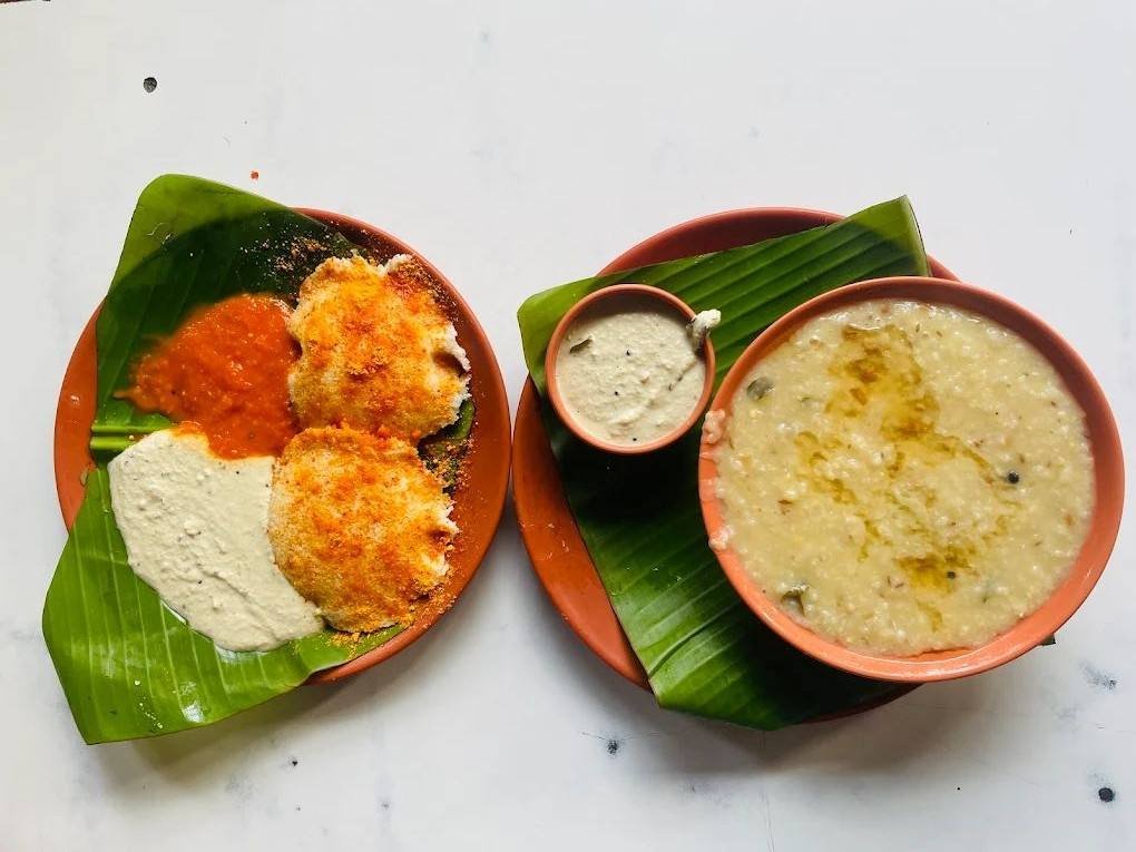 South Indian pongal and idli served on banana leaf with coconut chutney and red chutney