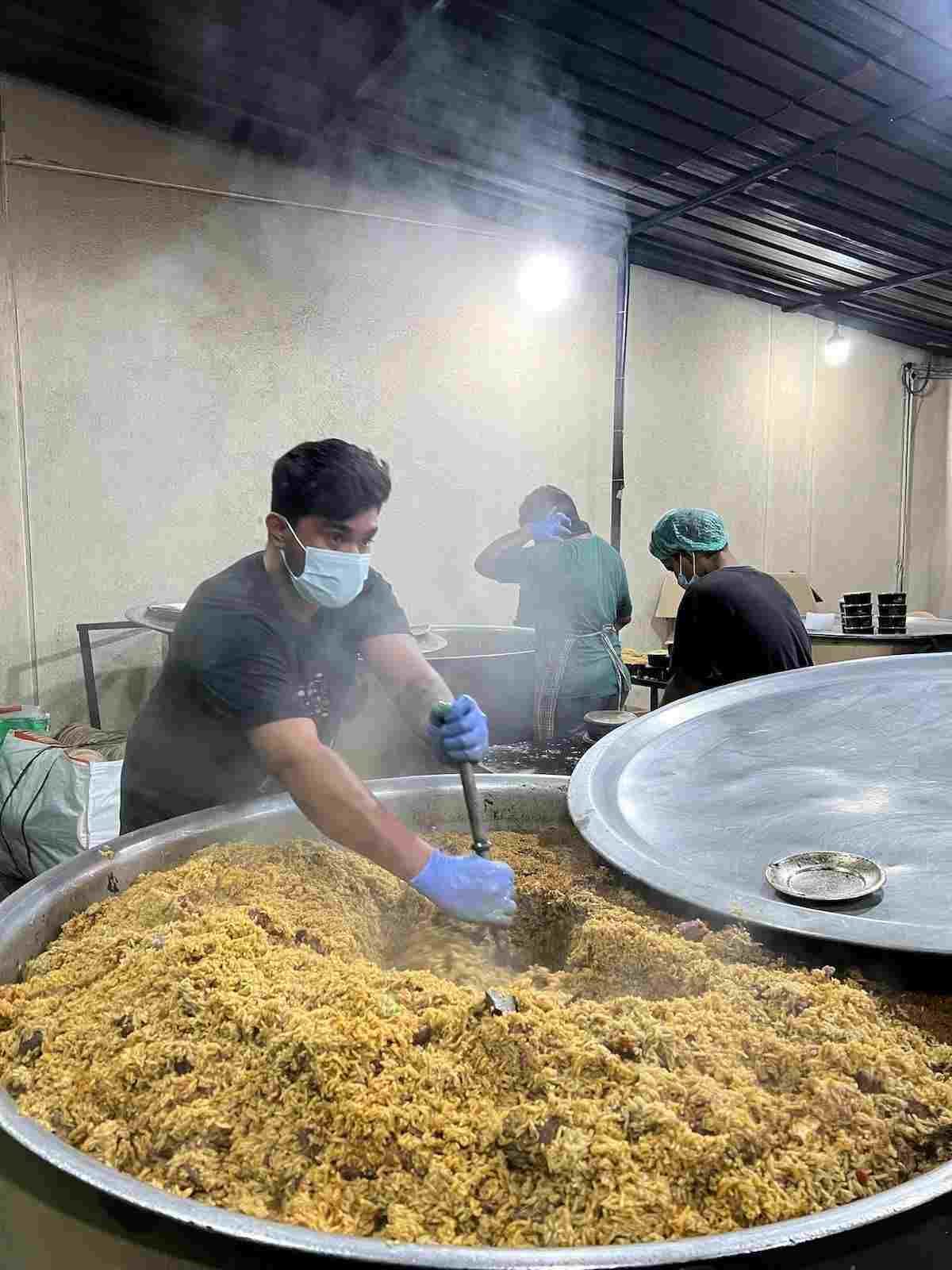 Chef preparing large batch of dum biryani in huge vessel at Raj Dum Biryani Hoskote