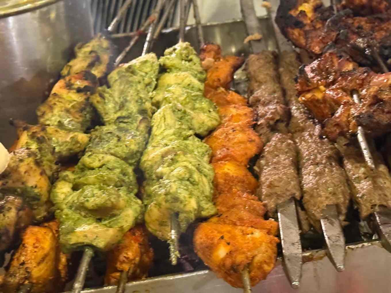 Seekh kebabs and grilled chicken tikka cooking at Bademiya Mumbai kebab grill