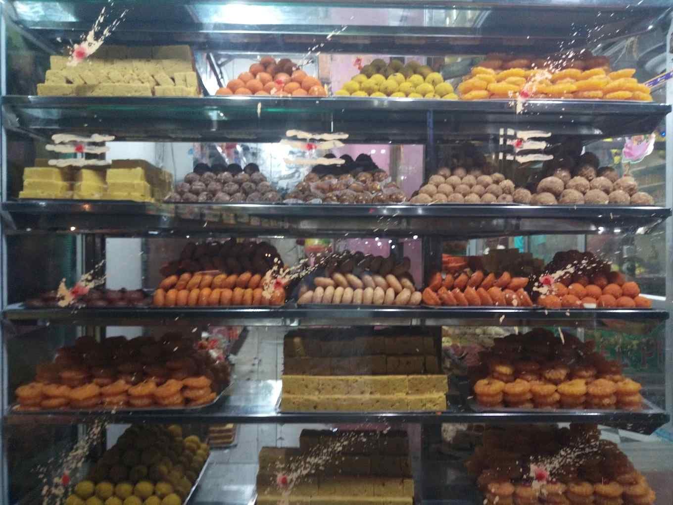 Traditional Indian sweets display at Hotel Ponni Dharmapuri featuring laddus, jangiri, gulab jamun, and bakery snacks