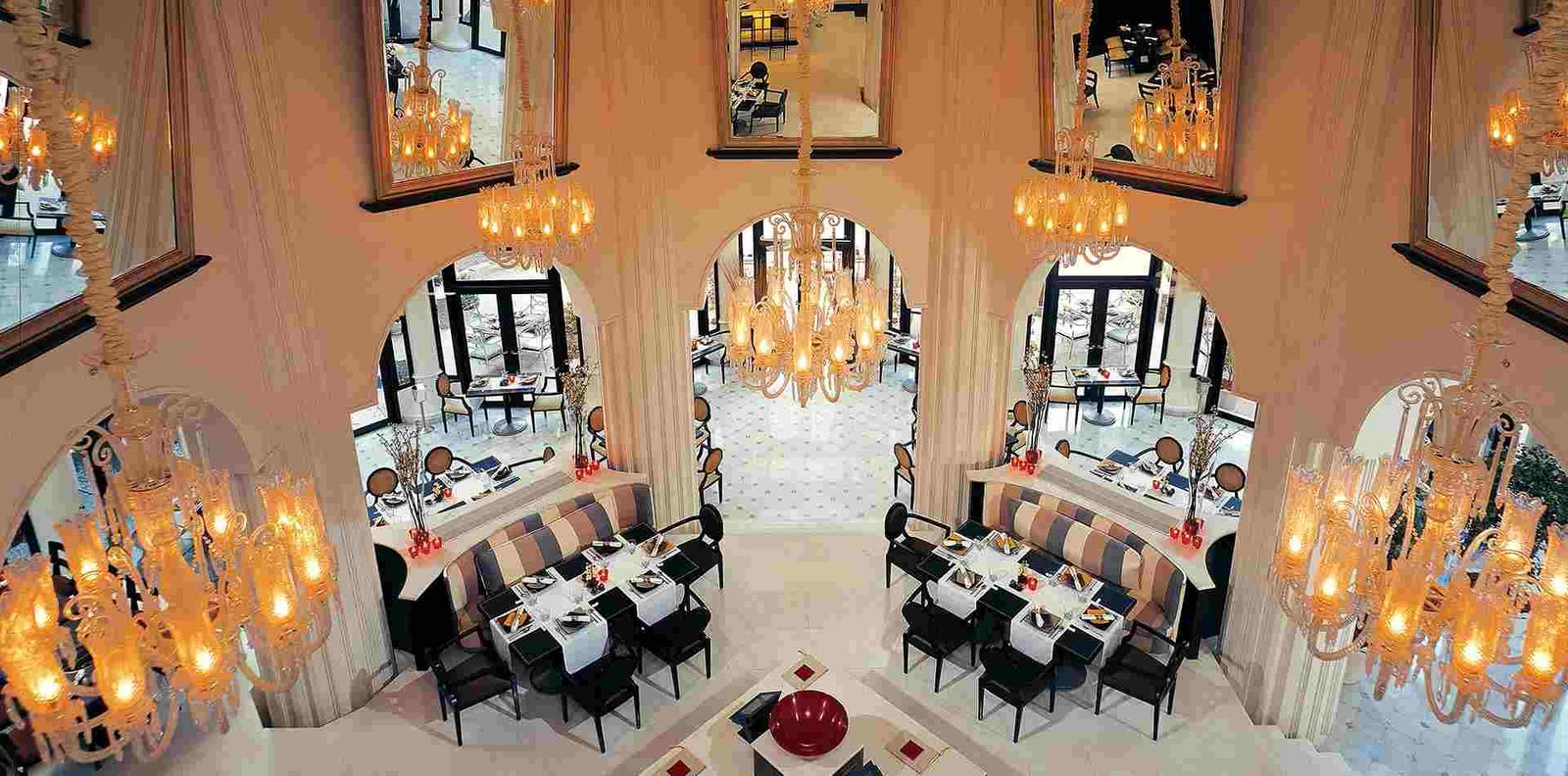 Elegant chandelier-lit dining area inside The Leela Palace Bengaluru with luxurious interiors and fine dining setup.