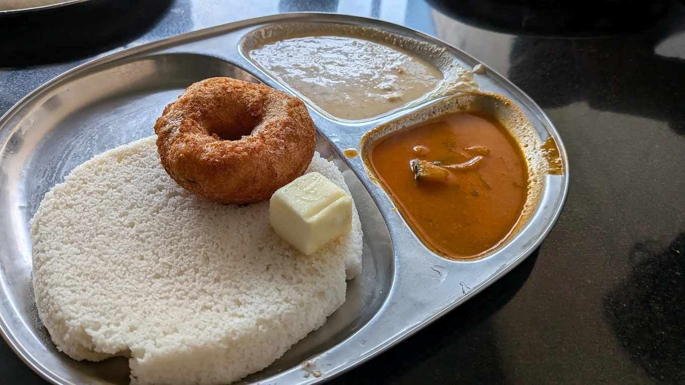 Soft idli and crispy medu vada served with chutney, sambar, and butter at Pavithra Idli Hotel.