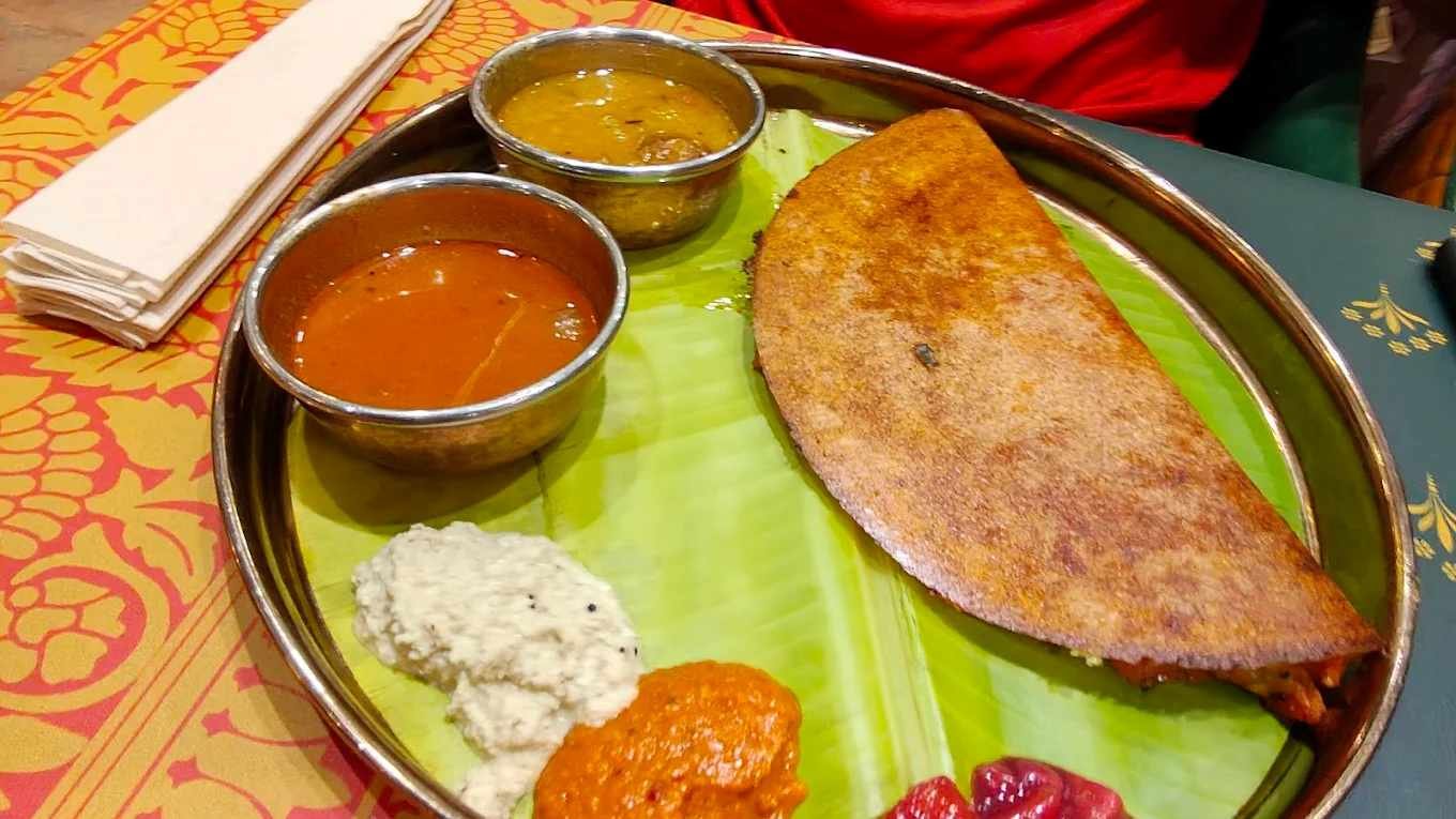 Crispy masala dosa served on a banana leaf platter with sambar and chutneys at Atithyaa restaurant in Bengaluru.