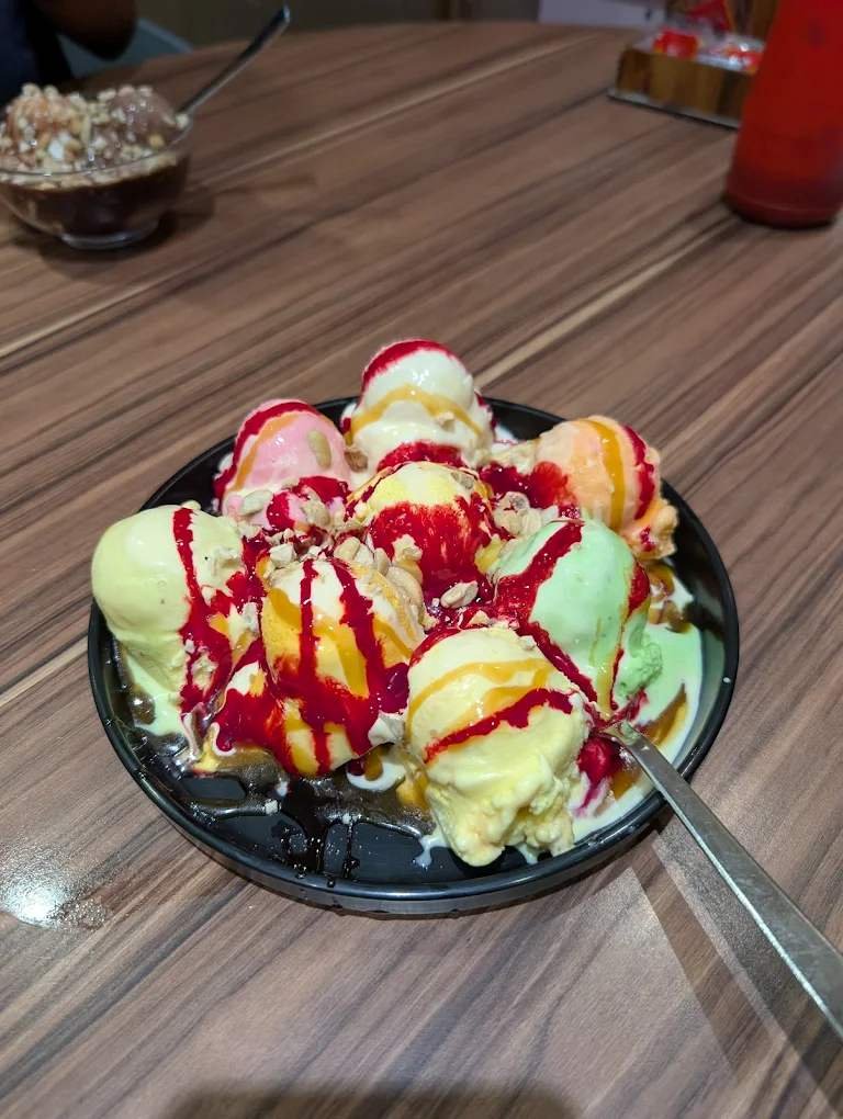Colorful ice cream sundae with multiple scoops and fruit syrup at Lakeview Milkbar Bengaluru
