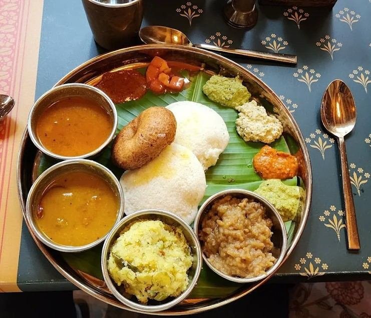 Soft idlis and crispy medu vada served with sambar, chutneys, and traditional accompaniments at Atithyaa Gandhi Bazaar.