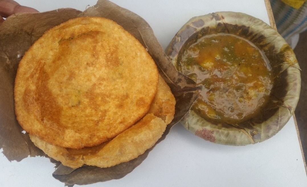 Traditional Varanasi-style kachori sabzi served on a leaf plate with spicy potato curry, a popular breakfast enjoyed in the holy city of Varanasi.
