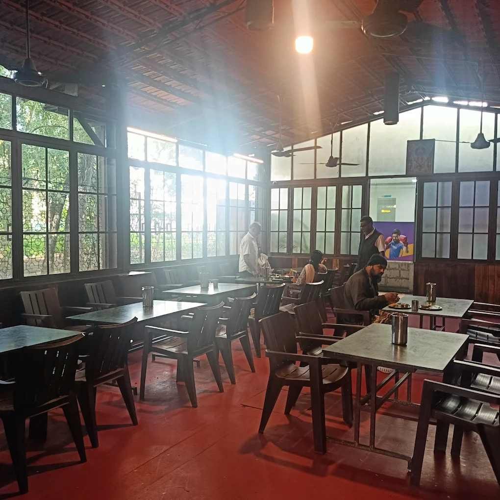 Spacious dining hall at Meenakshi Bhavan featuring wooden furniture, large windows, and a bright, welcoming atmosphere.