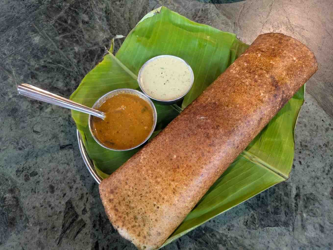 Crispy masala dosa served on a banana leaf with coconut chutney and sambar at Meenakshi Bhavan.