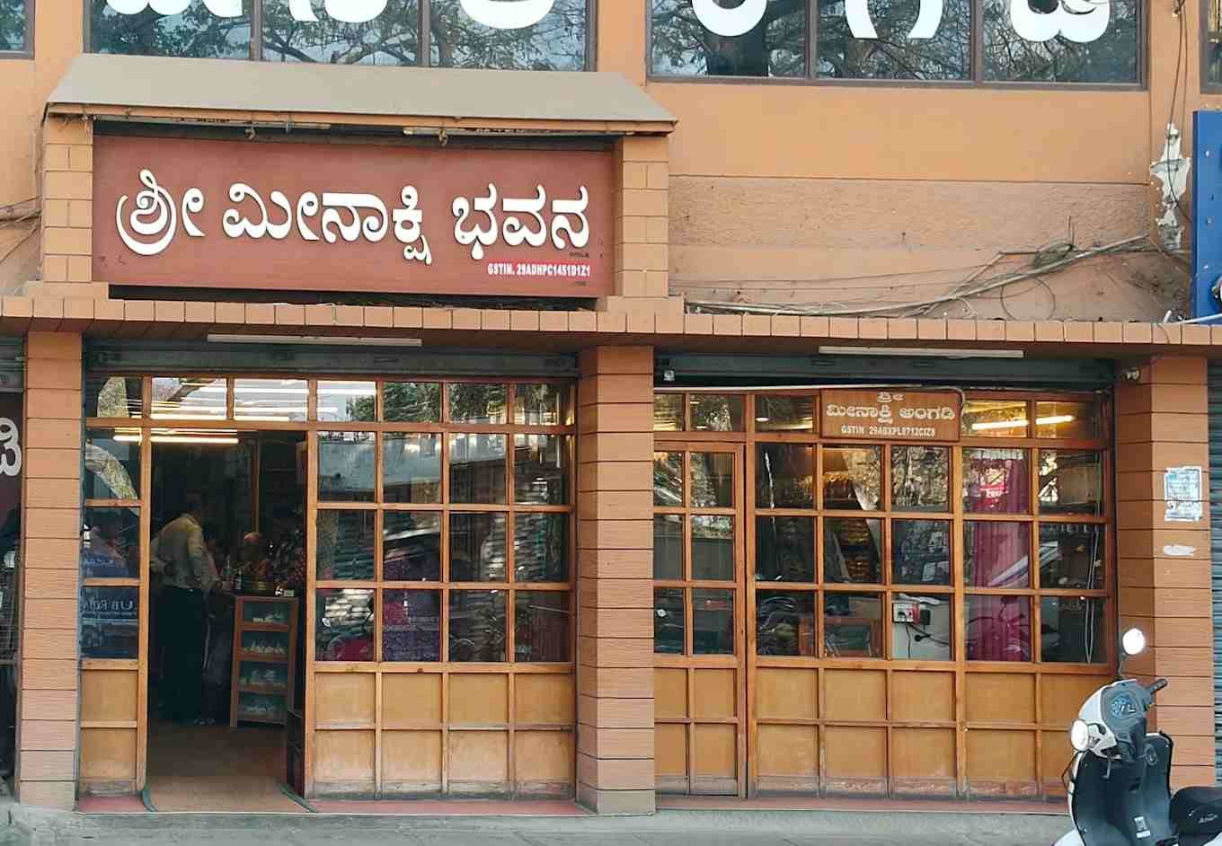 Front entrance of Meenakshi Bhavan restaurant with traditional signage and wooden-framed windows.